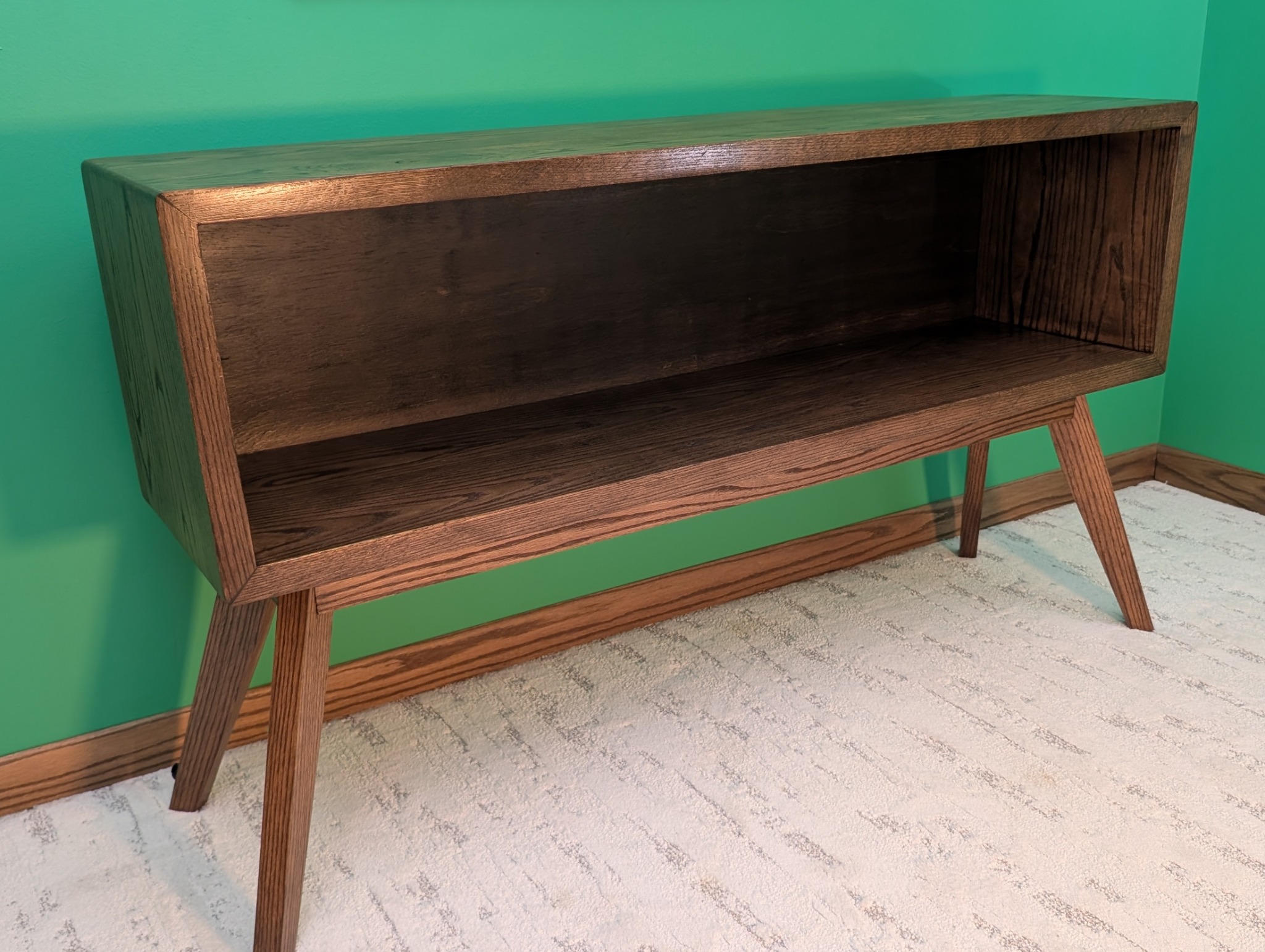 Empty oak console viewed at an angle to show its depth and splayed legs